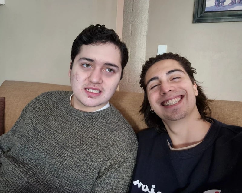 Carlos y Francisco hoy, sonriendo juntos en el sofá de su casa